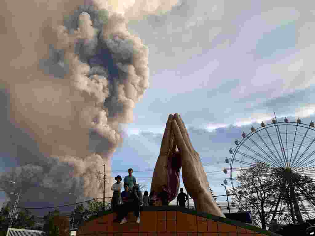 People watch as the Taal volcano spews ash and smoke during an eruption in Tagaytay, Cavite province south of Manila, Philippines.