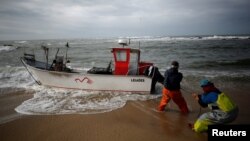 FILE - Fishermen pull a boat ashore at Angeiras beach near Matosinhos, Portugal, Feb. 12, 2018. (REUTERS/Pedro Nunes)