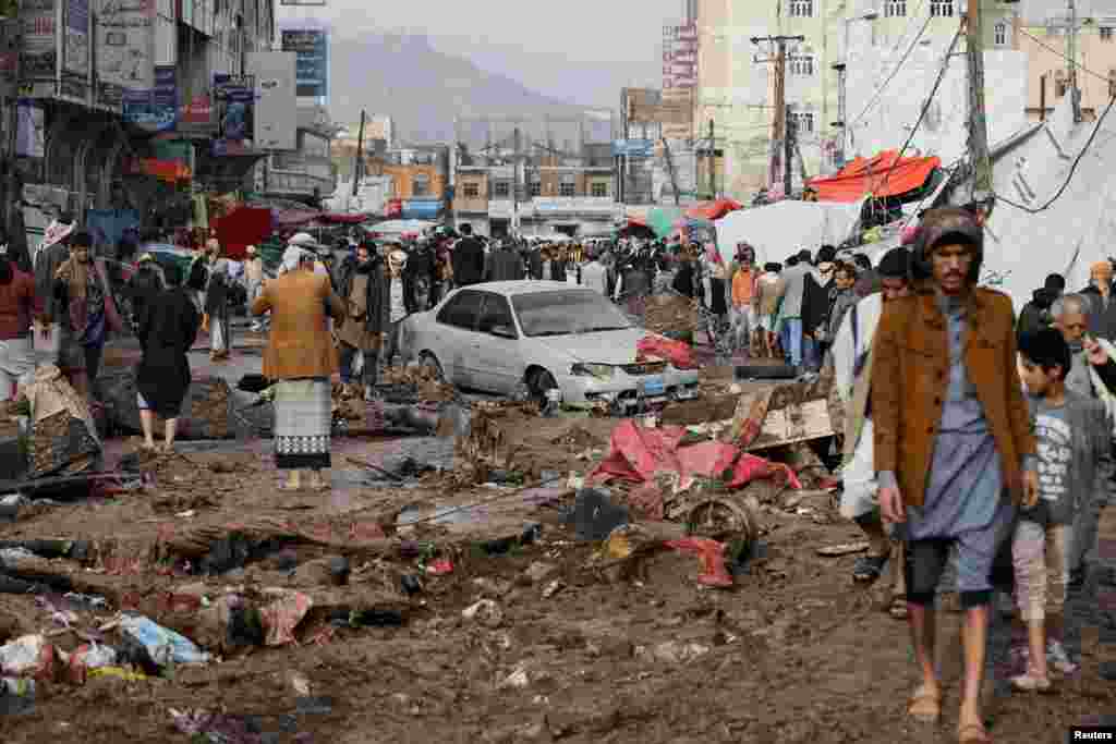 People walk on a damaged street in an area flooded by heavy rains in Sana&#39;a, Yemen.