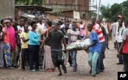 FILE - Men carry away a dead body in the Nyakabiga neighborhood of Bujumbura, Burundi, where a number of people were found shot dead a day after the government said an unidentified group had carried out coordinated attacks on three military installations, Dec. 1