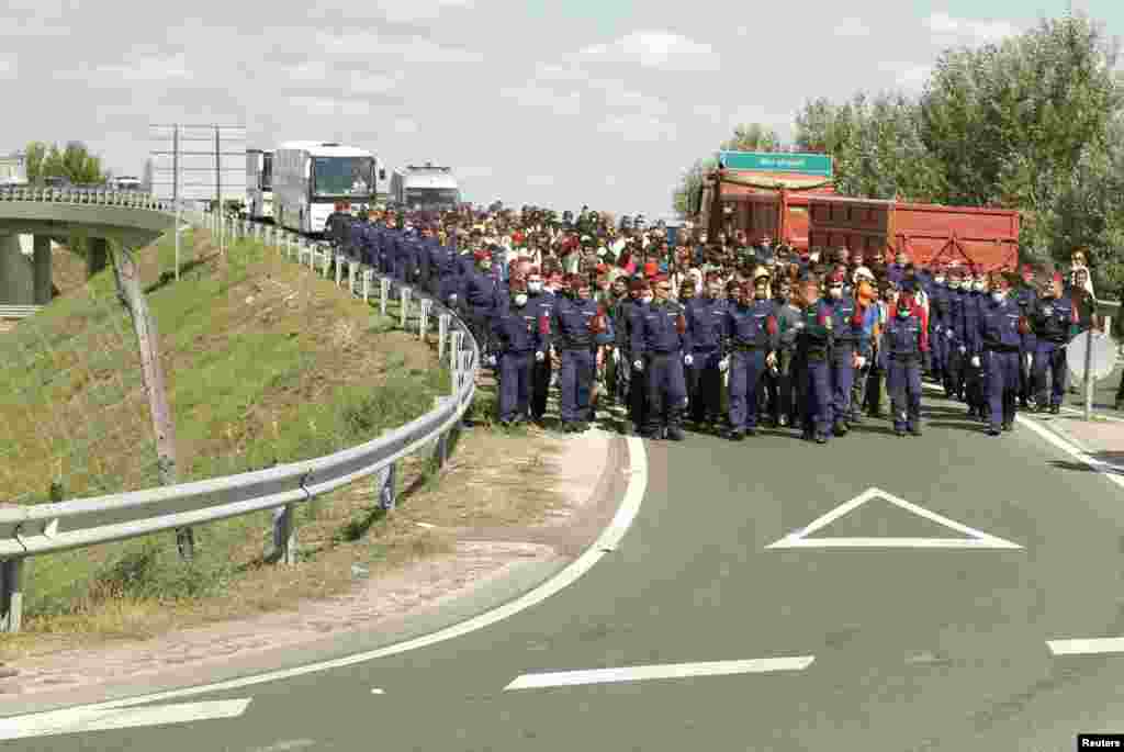 Hungary has closed its M5 highway after groups of migrants broke through a police cordon at Roszke on the border with Serbia and set off on foot towards the motorway, police said on their website. Police escort migrants back to a collection point in the village of Roszke.