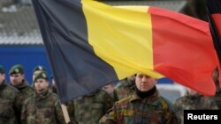 A Belgian soldier holds his national flag during a ceremony to welcome the German battalion being deployed to Lithuania as part of NATO deterrence measures against Russia in Rukla, Lithuania, Feb. 7, 2017.