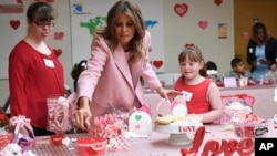 First lady Melania Trump, center, helps to fill candy boxes during a visit to the National Institutes of Health to see children at the Children's Inn in Bethesda, Md., to celebrate Valentine's Day, Feb. 14, 2019.