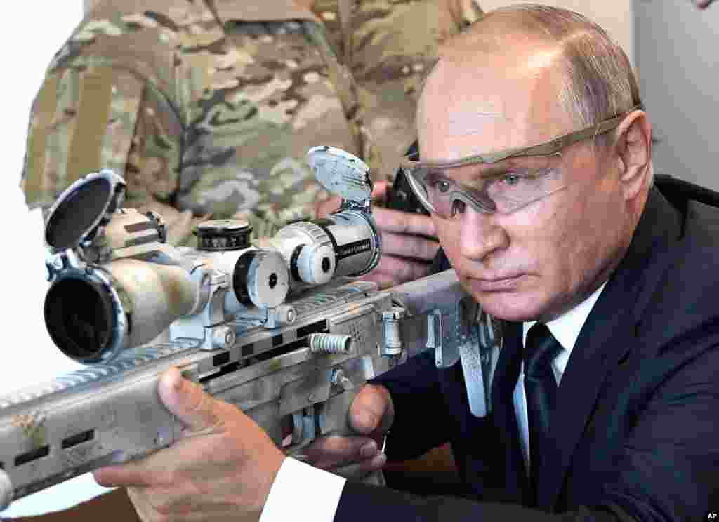 Russian President Vladimir Putin aims a sniper rifle during a visit to the Patriot military exhibition center outside Moscow, Russia.