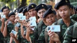 Tentara Thailand berpose dengan kartu identitas pemilih, menunggu waktu pemberian suara dalam Pemilu Thailand 2/2/2014. Mahkamah Konstitusi Thailand telah membatalkan pemilu itu. 