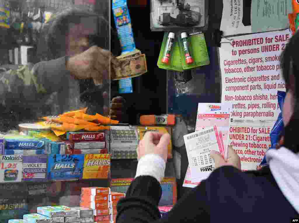 A woman (R) purchases Mega Millions lottery tickets in New York City, US. The Mega Millions jackpot currently is up to $970 million.