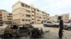 Un combattant loyal au gouvernement d'entente nationale (GNA) reconnu par l'ONU en Libye se tient à côté d'une voiture détruite suite à un bombardement à Tripoli, le 9 mai 2020. 
