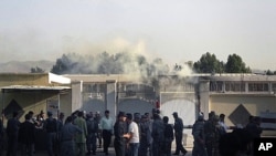 Afghan security stand outside the provincial governor's compound as smoke is seen rising from inside in Taloqan, Takhar province, north of Kabul, Afghanistan, May 28, 2011