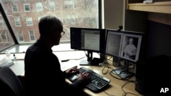 Brown University professor David Kertzer sorts through documents on his computer, including a photo of Pope Pius IX, in his office on the Brown campus in Providence, April 17, 2018.