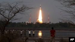 People watch as Indian Space Research Organization’s Geosynchronous Satellite Launch Vehicle Mk III rocket lifts off from the space launch center in Sriharikota, India, June 5, 2017. 