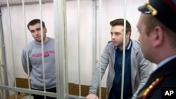 FILE - Opposition activists Alexei Gaskarov (L) and Ilya Gushchin (C) stand behind bars in a court room before hearings against opposition activists detained on May 6, 2012, during a rally at Bolotnaya Square, in Moscow, Russia, Thursday, April 24, 2014.