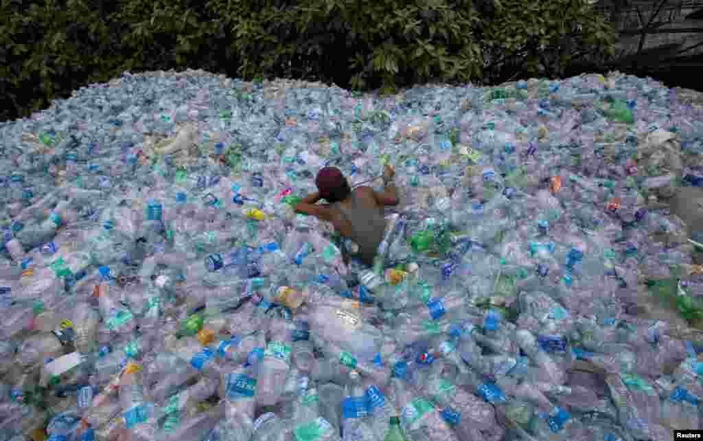A worker moves through a pile of empty plastic bottles at a recycling workshop in Mumbai, India.
