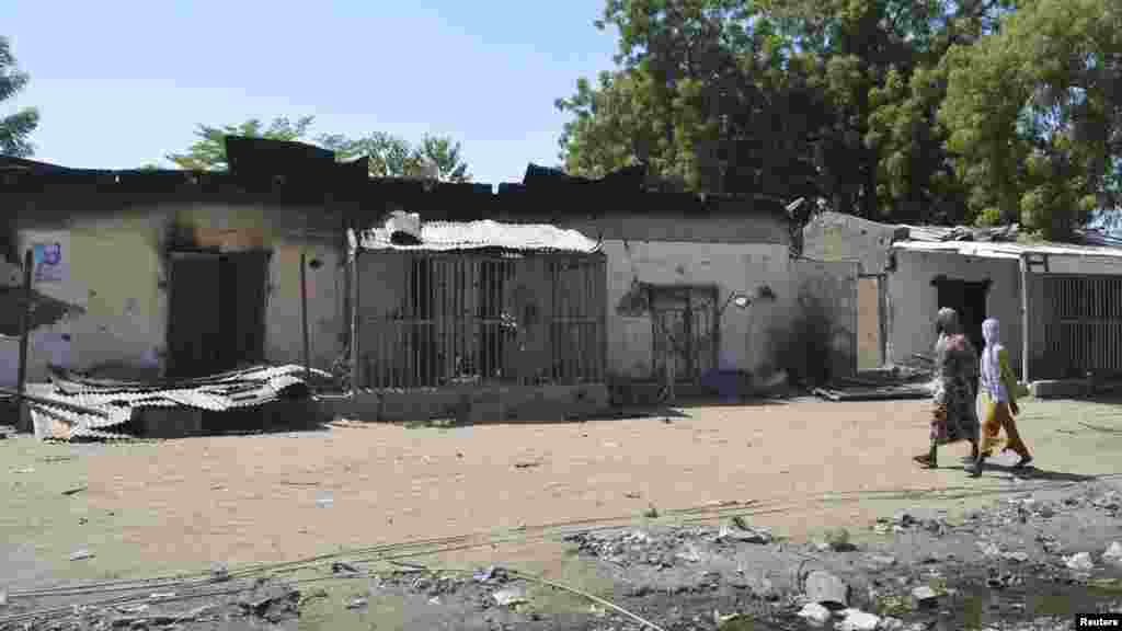 Mata na duba gidajen da harin Boko Haram ya lalata a garin Bama, Fabrairu 20, 2014.