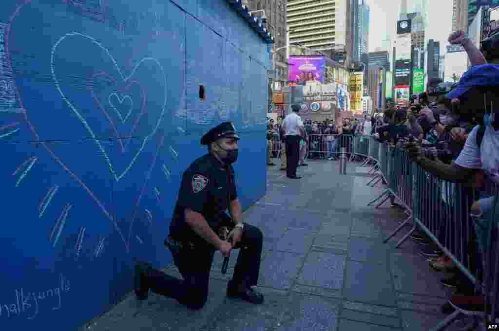 A New York City police officer takes a knee during a demonstration by protesters in Times Square, May 31, 2020, over the death of George Floyd while being held by police.