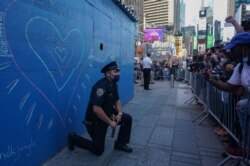 Seorang perwira polisi Kota New York berlutut saat demonstrasi atas kematian George Floyd di Times Square, 31 Mei 2020 di New York. (Foto: AFP)