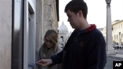 Seorang turis Amerika mengambil uang tunai di mesin ATM dekat kubah Basilika St. Peter, karena pembayaran elektronik sedang diblokir di Vatikan. (AP/Alessandra Tarantino)
