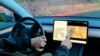 Seorang pemilik kendaraan Tesla di Portland, Oregon, menunjukkan cara kerja fitur video game yang dapat dimainkan saat kendaraan melaju pada 8 Desember 2021. (Foto: AP/Gillian Flaccus)