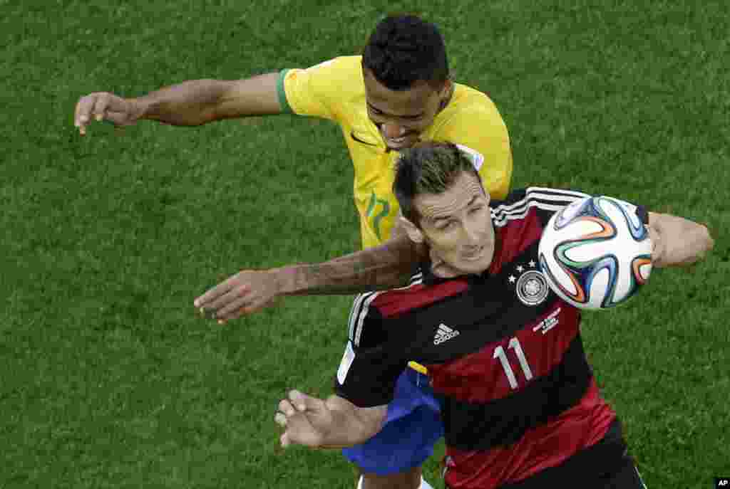Germany's Miroslav Klose and Brazil's Luiz Gustavo fight for the ball during the World Cup semifinal soccer match at the Mineirao Stadium in Belo Horizonte, Brazil, July 8, 2014.