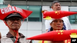 Protesters, wearing boat-shaped paper hats and mock missiles, join others in a rally at the Chinese Consulate to protest China's alleged continued militarization of the disputed islands in the South China Sea known as Spratlys, Feb. 10, 2018, in Makati city east of Manila, Philippines.