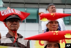 Protesters, wearing boat-shaped paper hats and mock missiles, join others in a rally at the Chinese Consulate to protest China's alleged continued militarization of the disputed islands in the South China Sea known as Spratlys, Feb. 10, 2018.