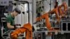 FILE - A man works amid orange robot arms at Rapoo Technology factory in southern Chinese industrial boomtown of Shenzhen. The country's trade with North Korea has slowed for the second consecutive year. 