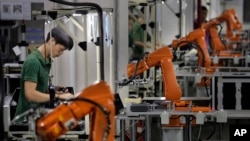 FILE - A Chinese man works amid orange robot arms at Rapoo Technology factory in southern Chinese industrial boomtown of Shenzhen. 