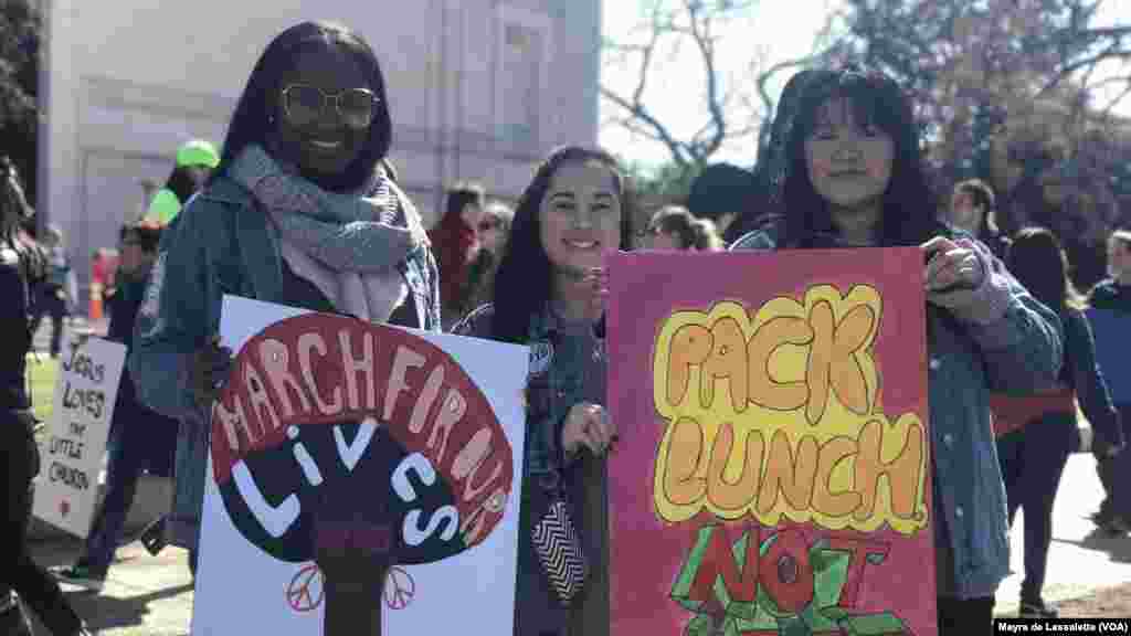 Quelques jeunes brandissent des pancartes lors de la manifestation à Washington DC, 24 mars 2018. 