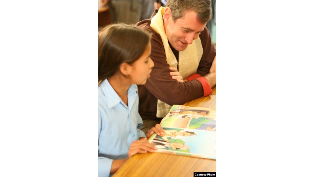 Pendiri Room to Read, John Wood, membaca dengan seorang anak di Nepal. (Andrea McTamaney)