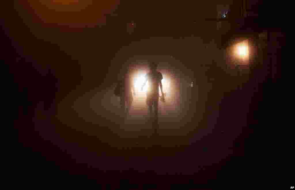 June 28: Tourists walk in dense fog caused by heavy rains on a street in the northern hill station town of Dharmsala, India. (AP Photo/Kevin Frayer)