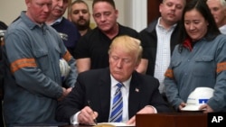 El presidente Trump firma la proclamación sobre las importaciones de acero durante una ceremonia en la que estuvo acompañado de trabajadores de esa industria.