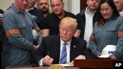 President Donald Trump signs a proclamation on steel imports during an event in the Roosevelt Room of the White House in Washington, March 8, 2018. He also signed one for aluminum.