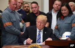 FILE - President Donald Trump signs a proclamation on steel imports during an event in the Roosevelt Room of the White House in Washington, March 8, 2018. He also signed one for aluminum.