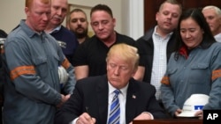 President Donald Trump signs a proclamation on steel imports during an event in the Roosevelt Room of the White House in Washington, March 8, 2018. He also signed one for aluminum.