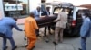 Des employés de Sopema Funerals chargent le corps d'une personne décédée dans un corbillard à Soweto, en Afrique du Sud, le 4 août 2020.