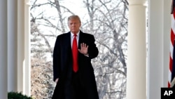 FILE - President Donald Trump waves as he walks through the Colonnade from the Oval Office of the White House on arrival to make an announcement.