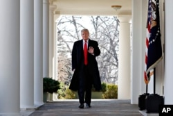 FILE - President Donald Trump waves as he walks through the Colonnade from the Oval Office of the White House on arrival to make an announcement.