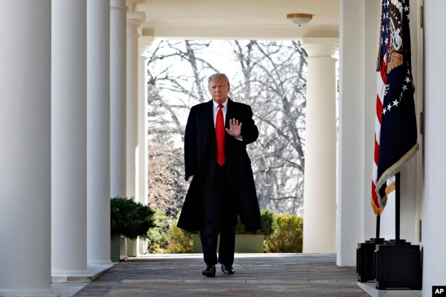 FILE - President Donald Trump waves as he walks through the Colonnade from the Oval Office of the White House on arrival to make an announcement.