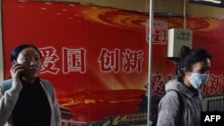 人們走過北京地鐵站入口處的“愛國，創新”宣傳廣告牌（2018年10月19日）。