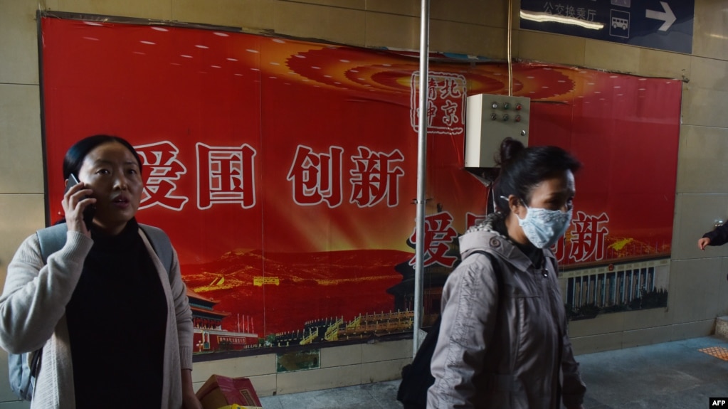 人们走过北京地铁站入口处的“爱国，创新”宣传广告牌（2018年10月19日）。(photo:VOA)