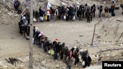 Rebel fighters queue as they wait to be evacuated from the Old City of Homs, May 8, 2014. 