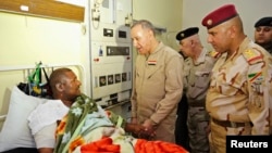 Iraqi Defense Minister Khaled al-Obeidi talks to a soldier wounded in the battle for Baiji during a hospital visit in Baghdad, Nov. 15, 2014. 
