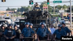 Riot police stand guard as demonstrators protest the shooting death of teenager Michael Brown in Ferguson, Missouri August 13, 2014.