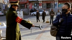 Polisi memeriksa pejalan kaki dengan detektor di sebuah jalan di Urumqi, Xinjiang Uighur. (Foto: Dok)