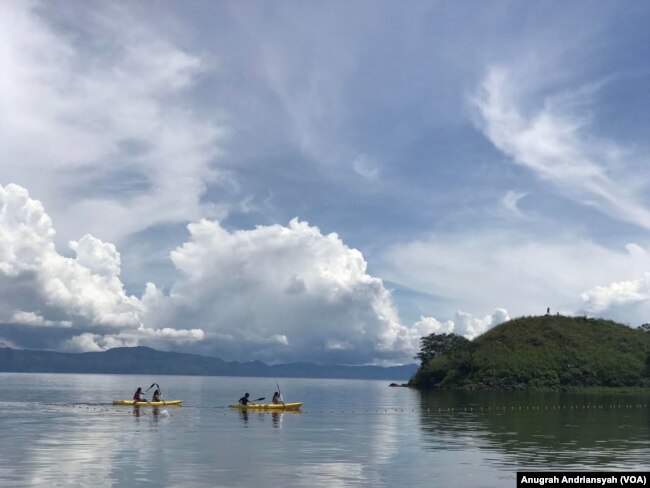 Dua orang warga tengah mengayuh sampan di Danau Toba, Sumatra Utara. (Foto: VOA/Anugerah Adriansyah) (Foto: Anugrah Andriansyah)