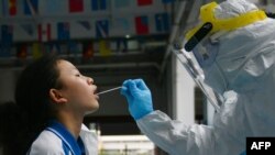 資料照片：一位醫務工作者用棉棒從一個學生口中獲取樣本進行新冠狀病毒核酸檢測。