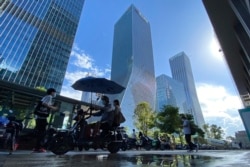 Residents pass near the headquarters for Evergrande in Shenzhen in southern China, Sept. 23, 2021.