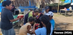 Kegiatan ibu-ibu mencari baju bekas di tenda pengungsian. (Foto: VOA/Yoanes)