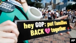 FILE - Samantha Montgomery of Denver holds up a sign during an immigration rally and protest in Civic Center Park, June 30, 2018, in downtown Denver.