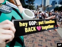 FILE - Samantha Montgomery of Denver holds up a sign during an immigration rally and protest in Civic Center Park Saturday, June 30, 2018, in downtown Denver.