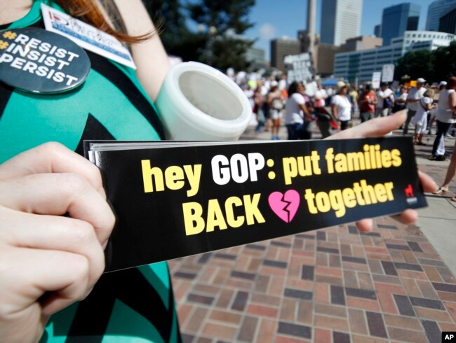 FILE - Samantha Montgomery of Denver holds up a sign during an immigration rally and protest in Civic Center Park Saturday, June 30, 2018, in downtown Denver.